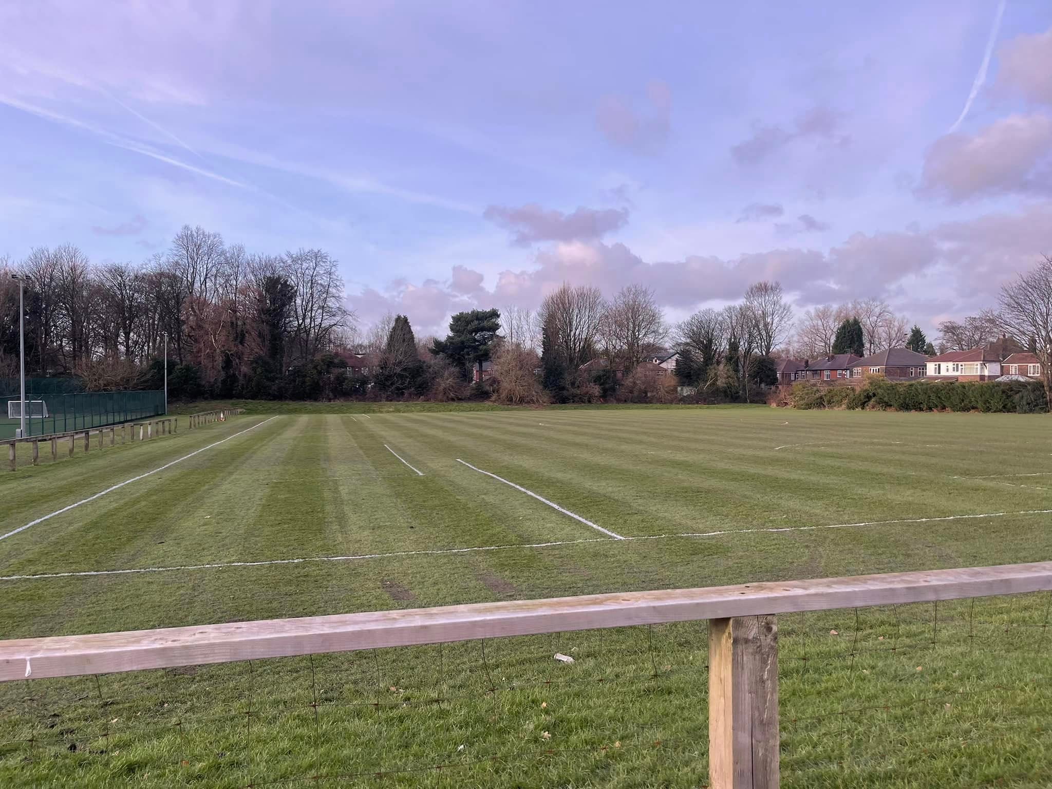 A freshly marked grass pitch under a dusk sky